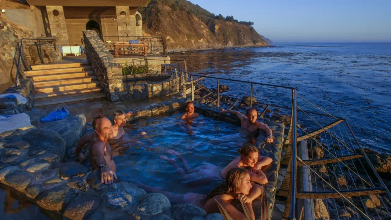 People soaking in the Esalen baths, looking out across the Pacific Ocean